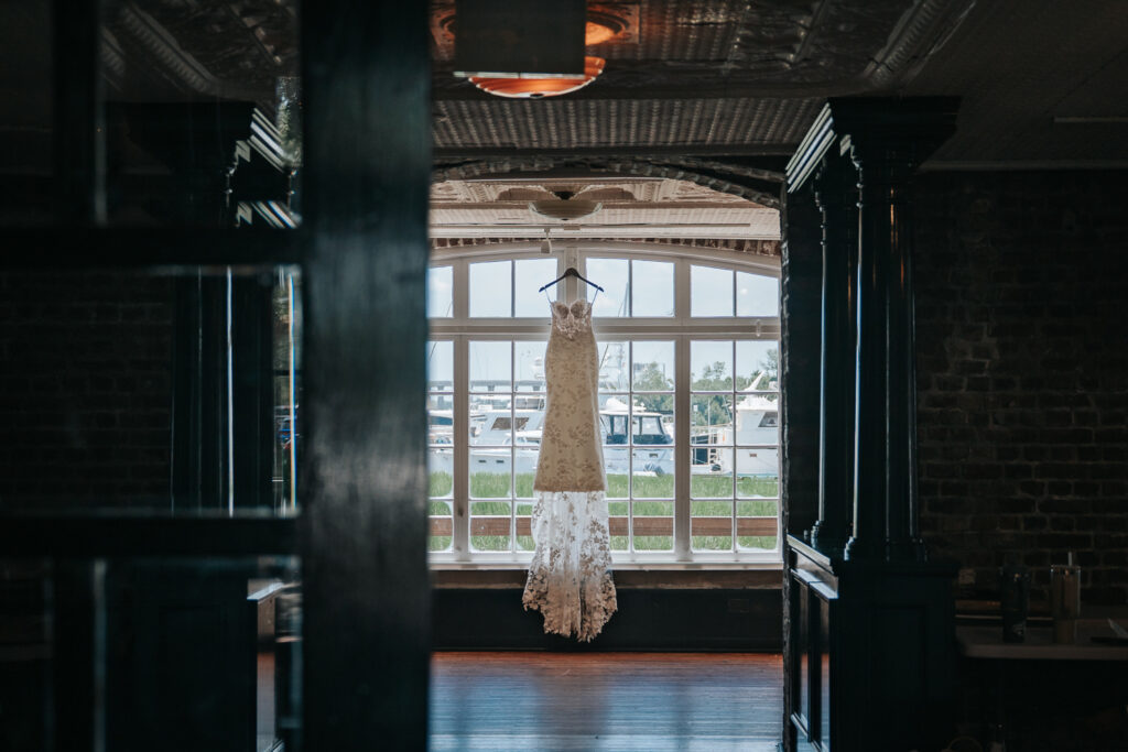 wedding dress by Gown boutique of charleston hanging in the historic rice mill